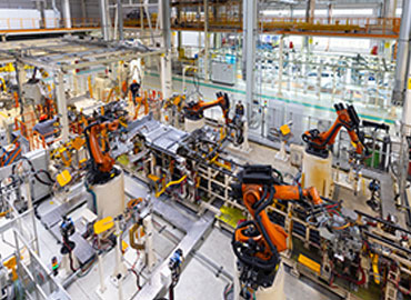 Innenansicht einer Smart Factory in der Automobilindustrie, in der mehrere Roboterarme an der Montage von Fahrzeugkarosserien arbeiten. Die automatisierte Produktionslinie zeigt eine hochmoderne, vernetzte Umgebung.
